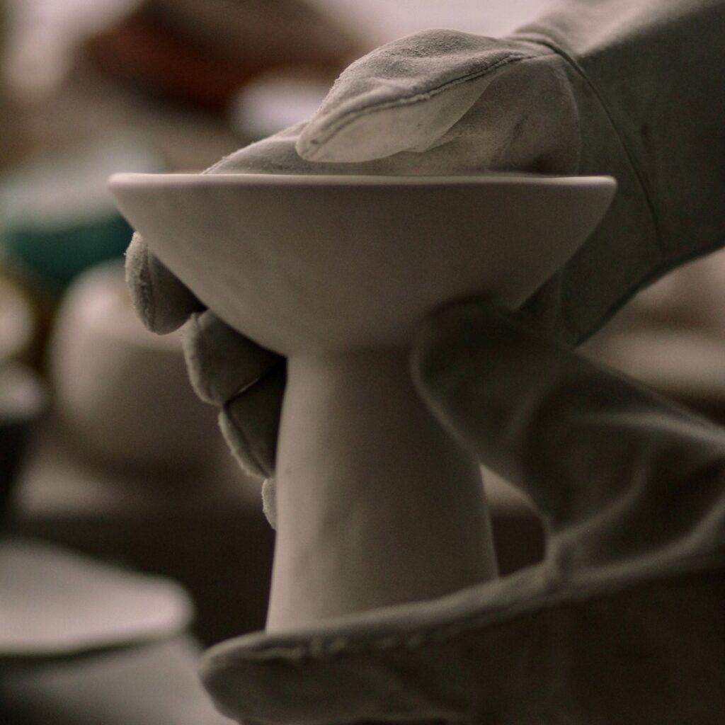hands-wearing-heat-protective-kiln-gloves-holding-a-piece-of-fired-ceramic-pottery