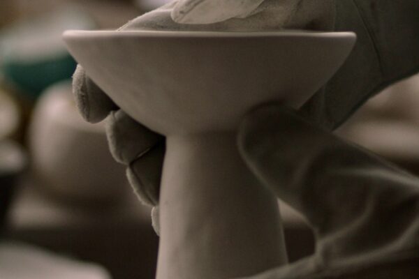 close-up-view-of-hands-in-kiln-gloves-picking-up-a-piece-of-fired-pottery-out-of-a-kiln