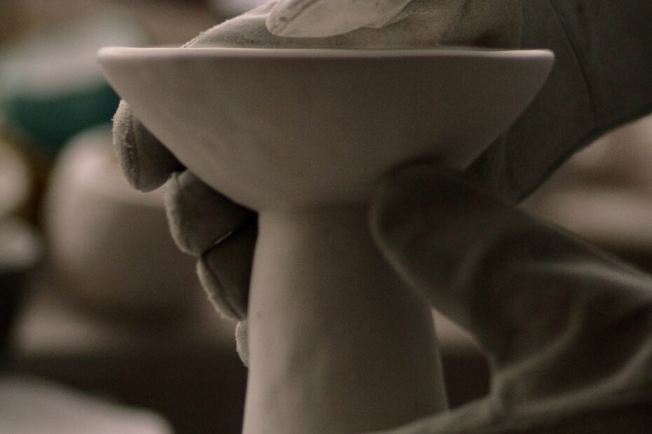 close-up-view-of-hands-in-kiln-gloves-picking-up-a-piece-of-fired-pottery-out-of-a-kiln